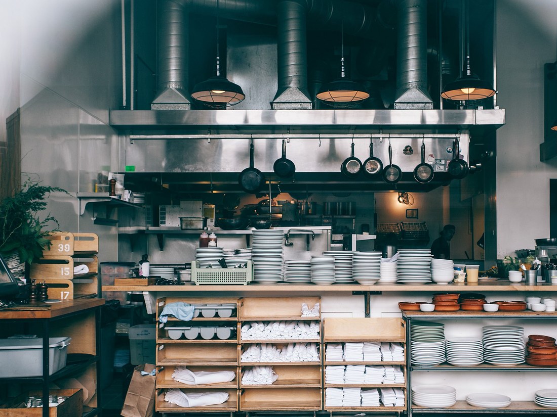 A professional restaurant kitchen pass with plates, pans and equipment organised for service