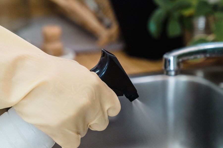 Gloved hands sanitising a food preparation surface